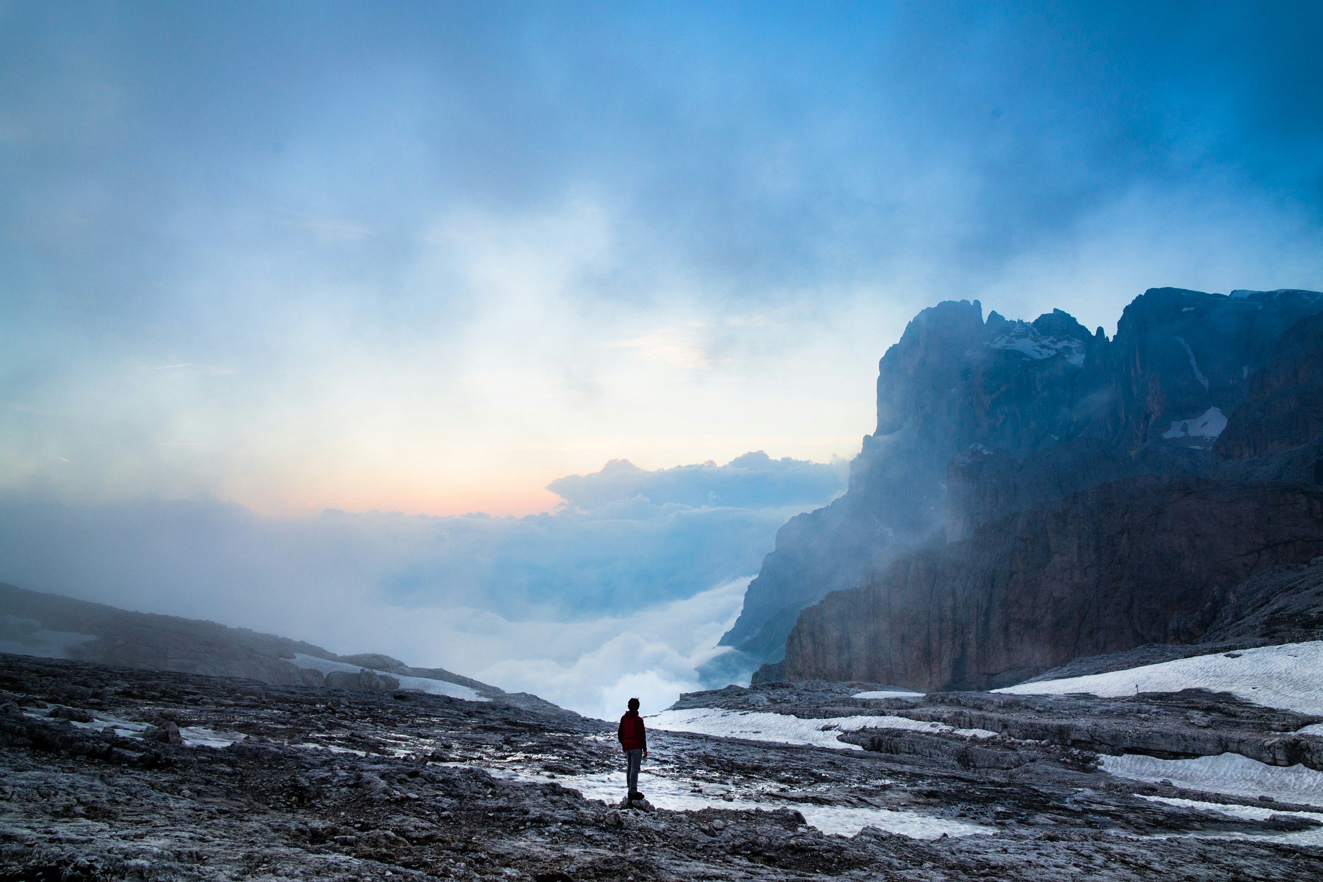 person standing near the cliff of the mountain